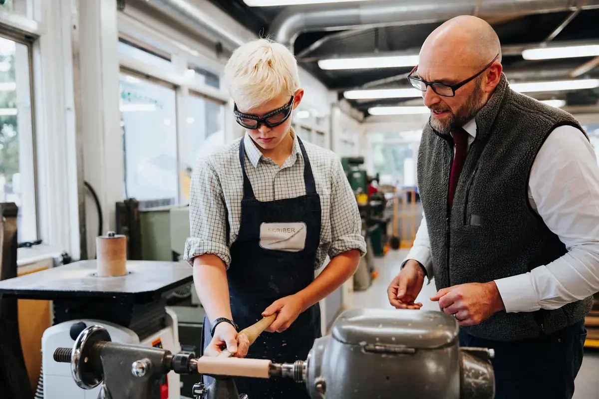 Student learning wood turning skills with the design and technology teacher.
